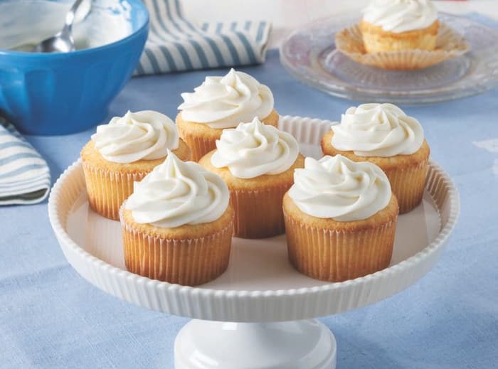 Six Vanilla Frosted Cupcakes On Cake Stand