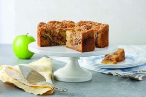 Apple Streusel Cake On Stand With Cake Cutter And Plated Slice