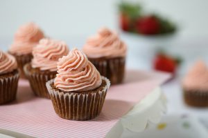 cupcakes topped with swirls of pink strawberry mascarpone cream cheese frosting